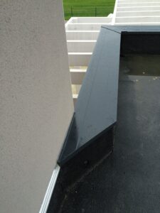 Couvertine alu grise pour protéger l'étanchéité d'un toit terrassée. Pose effectuée par Bourguignon Dal'alu le long du mur de façade blanc.
